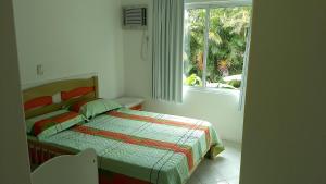 1 dormitorio con cama y ventana en Apto com 02 quartos Praia da Conceição Bombinhas SC, en Bombinhas
