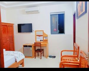 una camera con letto, scrivania e TV di Minh Quân hotel a Vung Tau