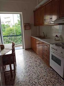 kuchnia z kuchenką, stołem i oknem w obiekcie MARIAS APARTMENT SMART KEY BOX by PROJECT 86 IKE w mieście Agrinio
