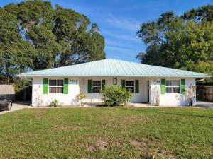 een wit huis met een groen dak en een tuin bij Beachy Sarasota Duplex in Sarasota
