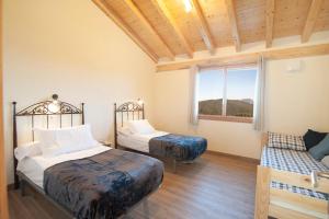 1 dormitorio con 2 camas, ventana y sofá en La Asomada de Vidular en Bárcena de Cicero