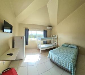 1 dormitorio con 1 cama y escritorio en una habitación en Pousada Girassol da Ferrugem, en Garopaba