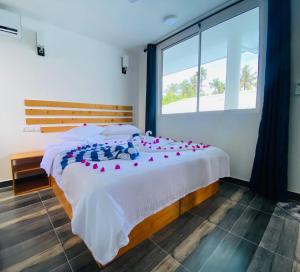 a bedroom with a large bed with red roses on it at Ramzu Villa Thoddoo in Thoddoo