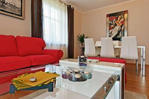 a living room with a red couch and a table at Glamour Apartments Sopot in Sopot