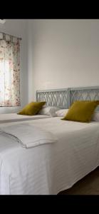 1 cama blanca grande con 2 almohadas verdes en HOSTAL LA CRUZ 1872, en Chipiona