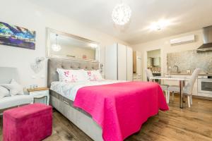 Un dormitorio con una cama grande con una manta rosa. en Apartments Stella Mariela, en Šibenik