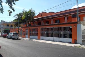 un edificio naranja con un coche blanco aparcado delante de él en Appartamenti Melissa, en Playa del Carmen