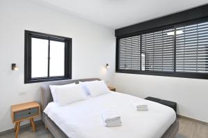 1 Schlafzimmer mit einem weißen Bett und 2 Fenstern in der Unterkunft Summer Off by HolyGuest in Tel Aviv