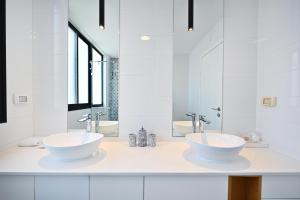 ein weißes Badezimmer mit zwei Waschbecken und Spiegeln in der Unterkunft Summer Off by HolyGuest in Tel Aviv