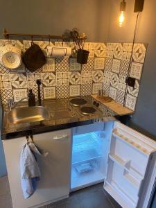 eine Küche mit einer Spüle und einem offenen Kühlschrank in der Unterkunft Le petit 19 in Jodoigne