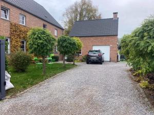 a driveway with a car parked in front of a house at Le petit 19 in Jodoigne