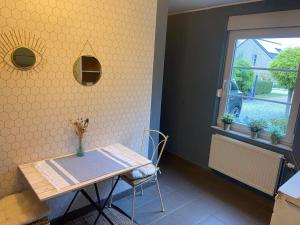 uma mesa e cadeira num quarto com uma janela em Le petit 19 em Jodoigne