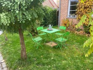 einen Tisch und Stühle in einem Garten mit einem Baum in der Unterkunft Le petit 19 in Jodoigne