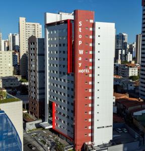 a tall red hotel building in a city at Stop Way Hotel Fortaleza in Fortaleza