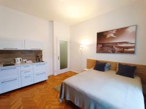 a white bedroom with a bed and a kitchen at Apartmen -Studio in Prague