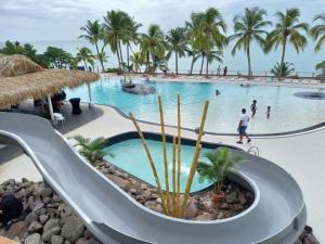 a slide at a resort with people in a swimming pool at Appart 'Caraibe Résidence MARINE HOTEL in Le Diamant