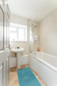 a white bathroom with a sink and a bath tub at Stepney Green beds to stay 24 in London