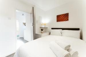 a white bedroom with a large bed with white sheets at Stepney Green beds to stay 24 in London