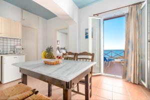 een keuken met een tafel en uitzicht op de oceaan bij Reggina's Apartments in Finikas