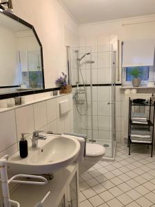 a white bathroom with a sink and a shower at Ferienwohnung Kaspers in Schalkenmehren
