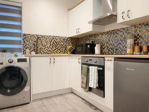 a kitchen with white cabinets and a washer and dryer at Lovely and comfy entire 1 bedroom flat - 1st floor in Harrow on the Hill