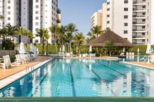 a swimming pool in a resort with buildings in the background at Especial Riviera! Condominio Acqua a 30 seg da praia - tipo resort - apto com ar condicionado, wifi, aceita pet in Riviera de São Lourenço