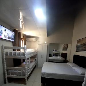 a room with two bunk beds and a tv at Suítes Itaigara a 80 metros da praia do Mariscal in Bombinhas