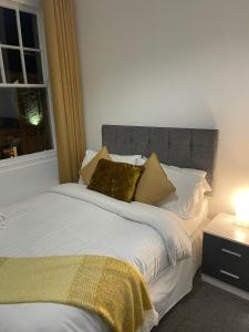 a bed with white sheets and gold pillows next to a window at Ship Inn Stays Ltd in Wylam