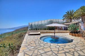 a small pool with an umbrella and the ocean at Cielo Y Mar in Puntallana
