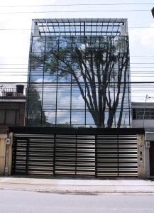 un edificio con un reflejo de árbol en las ventanas de un garaje en Apartasuites AAA Modelia Bogotá, en Bogotá