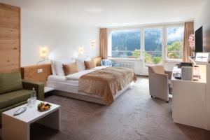 een slaapkamer met een bed en een woonkamer bij Hotel Waldegg - Adults only in Engelberg