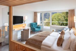 a bedroom with a bed and a desk and a tv at Hotel Waldegg - Adults only in Engelberg