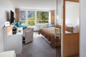 a hotel room with a bed and a desk and a window at Hotel Waldegg - Adults only in Engelberg