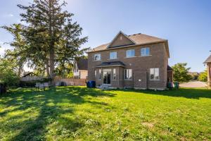 a house with a grassy yard in front of it at Beautiful Family Villa, Pond Facing with Huge Backyard in Brampton