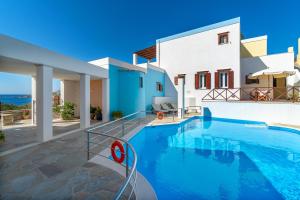a villa with a swimming pool in front of a house at Reggina's Apartments in Finikas