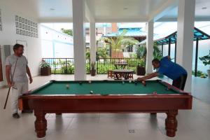 dos hombres jugando al billar en una mesa de billar en Morona Flats & Pool - 150 m2, en Iquitos