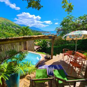 a deck with a pool and chairs and an umbrella at Vila Bambu Ilhabela, Santa Tereza in Ilhabela