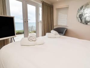 a bedroom with two beds with a tv and a window at Viridian in Carbis Bay