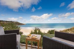 a patio with a table with a view of the beach at Viridian in Carbis Bay