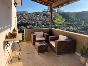 a balcony with chairs and a view of a city at Estadia das Gerais - Suíte Privativa 5 in Ouro Preto