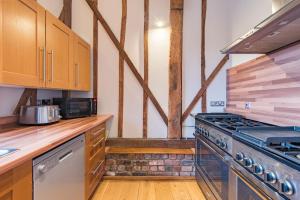 a kitchen with wooden cabinets and a stove at The Canterbury Barn by Bloom Stays in Canterbury