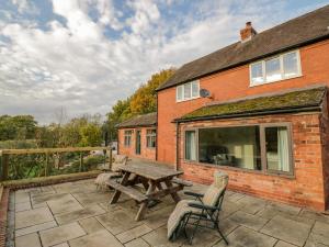 a patio with a wooden picnic table and chairs at Meadowfields in Kidderminster