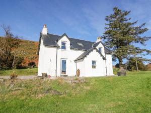 una casa blanca en un campo con un árbol en Bourblach en Mallaig