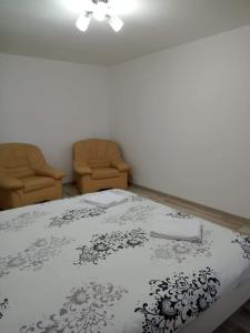 a bedroom with a bed and two chairs at Criss Apartament in Suceava