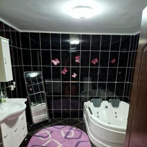 a bathroom with a black tiled wall with pink butterflies at Ciprians' Home in Săcele