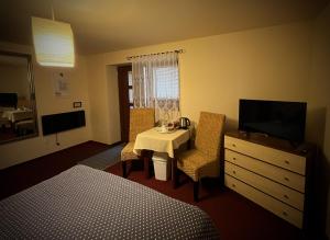 a hotel room with a table and a tv and a bedroom at Penzión Pri Kaštieli Záturčie in Martin