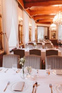 uma sala de jantar com mesas brancas e cadeiras com flores em Hotel Zamek Chałupki em Ruderswald