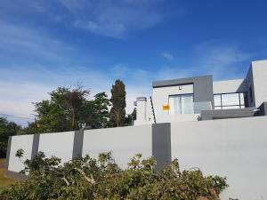 a house with a white wall in front of it at Alcade Ekhaya in Pretoria