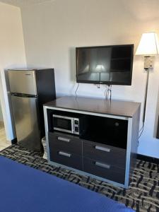 a tv on top of a dresser with a refrigerator at Homelodge Newnan in Newnan