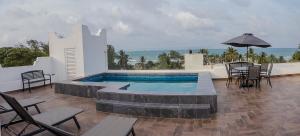 a swimming pool with chairs and a table and an umbrella at Hotel Boketto in Tuxpan de Rodríguez Cano